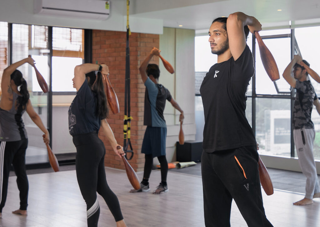 coaches beginning to teach indian clubs, he is holding & everyone is watching